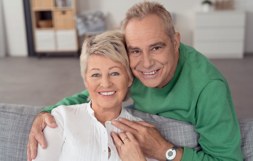 Older couple smiling together with a pendant alarm visible