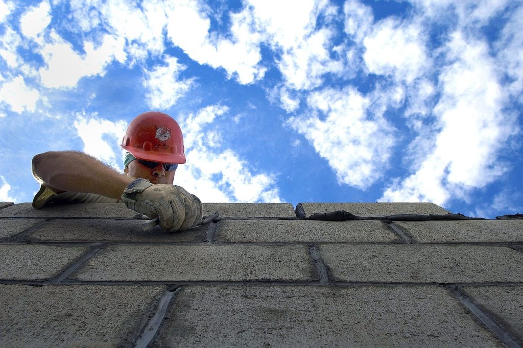 Construction worker in a hard hat viewed against a blue sky