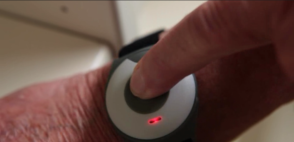 Close-up of a finger pressing a wrist-worn alarm button
